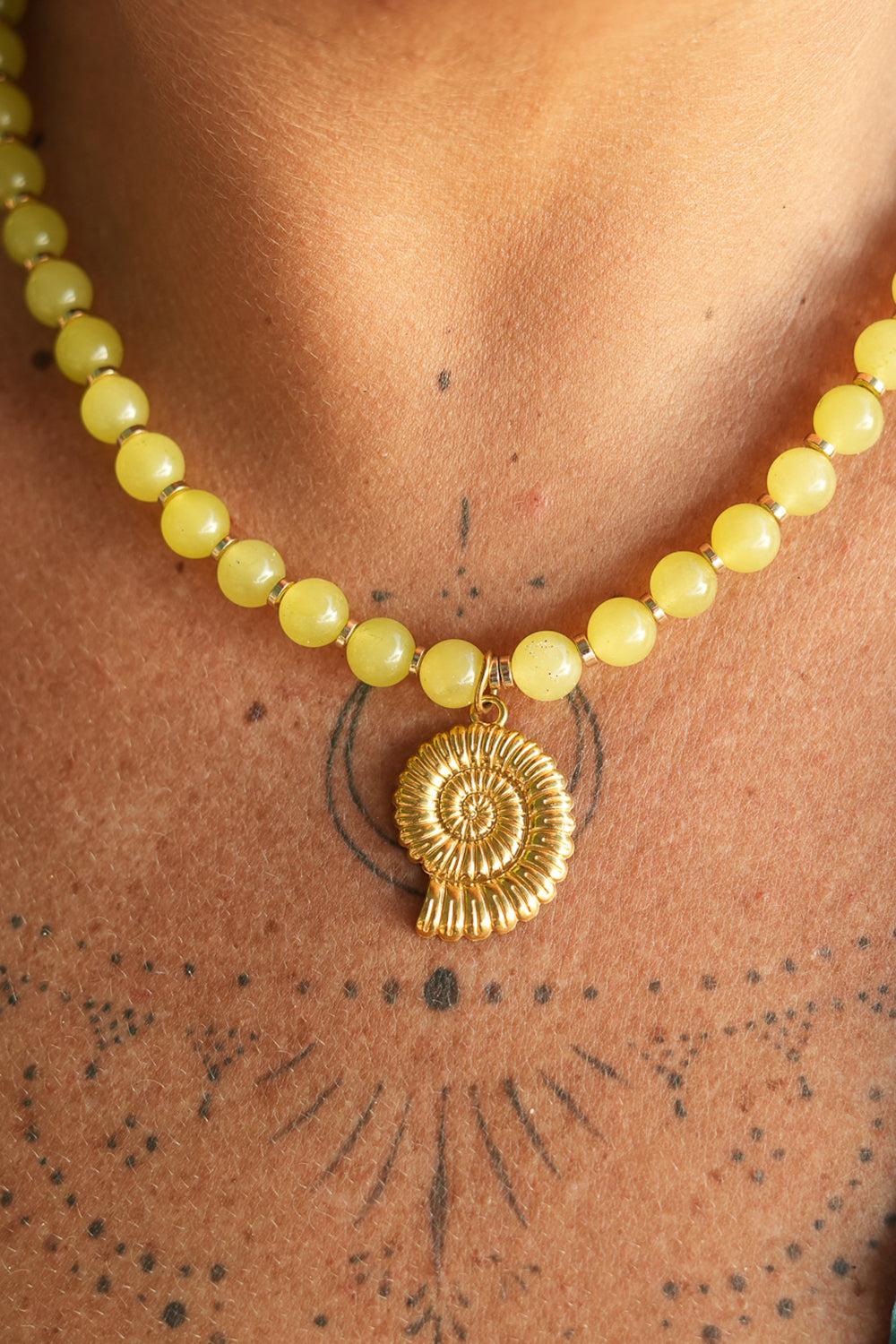 Shop the Ammonite Necklace in Solar Jade Gold, with natural yellow stone beads and a sculpted gold spiral shell pendant from Earth Altering by Jinx the Label.
