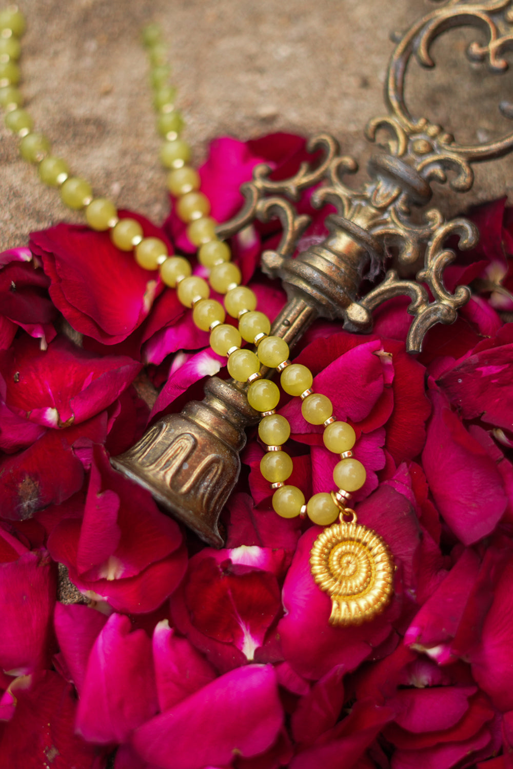 Shop the Ammonite Necklace in Solar Jade Gold, with natural yellow stone beads and a sculpted gold spiral shell pendant from Earth Altering by Jinx the Label.