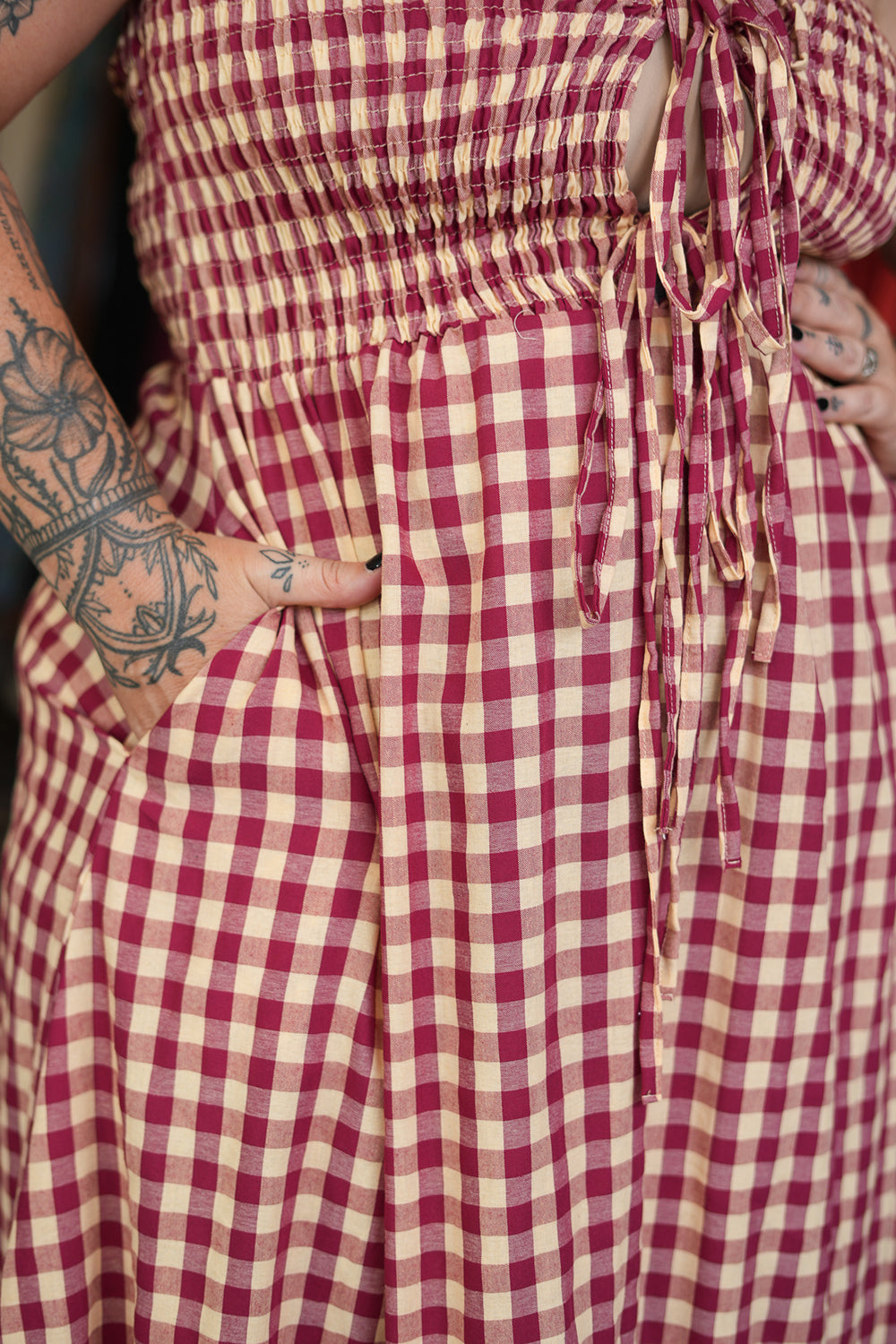 Meet the Mayana Maxi Dress in Wine Cream from Nevada. A dreamy rayon gingham maxi with shirring, adjustable front ties, a flowing ruffled skirt and pockets.