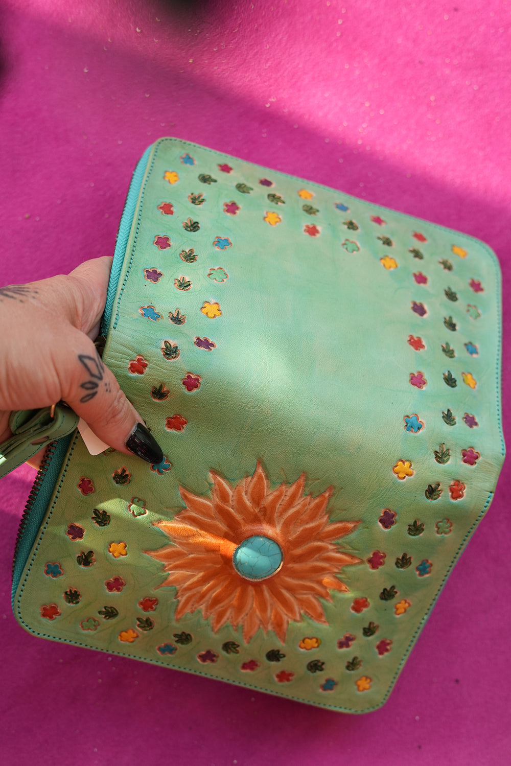 Meet the Mojave Wallet in Desert Mint. A hand tooled leather wallet with sunflower detailing, turquoise accents, card slots, coin compartment and wrist strap.