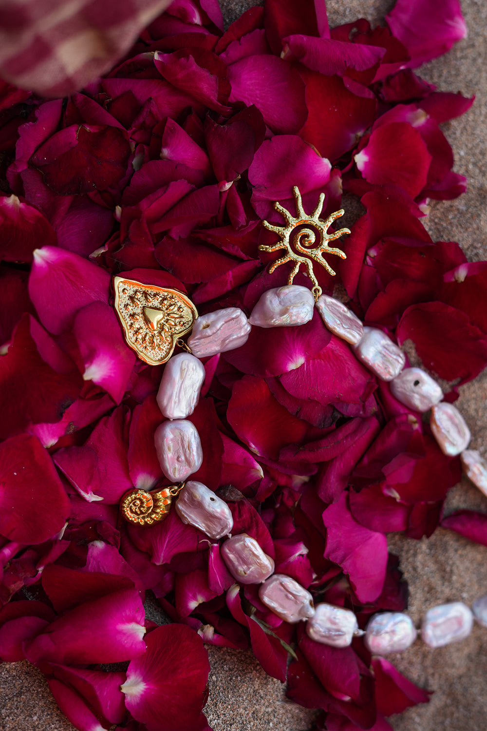 Discover the Sacred Love Necklace in Blush Pearl, featuring irregular freshwater pearls and gold sacred heart, sun and spiral charms by Jinx the Label.
