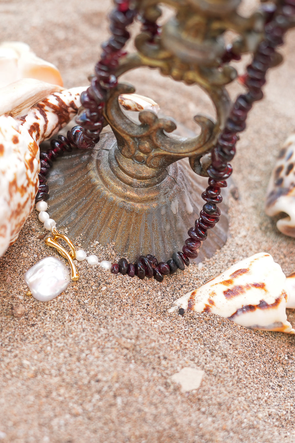 Discover the Wild Heart Necklace in Garnet, featuring deep natural garnet stones, freshwater pearls, a gold toggle and luminous baroque pearl by Jinx the Label.