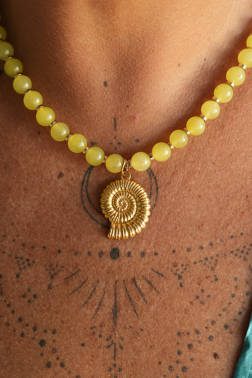 Shop the Ammonite Necklace in Solar Jade Gold, with natural yellow stone beads and a sculpted gold spiral shell pendant from Earth Altering by Jinx the Label.