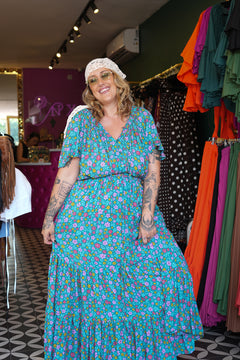 Meet the Dainty Dress in Aqua Bloom, a flowing rayon maxi with an adjustable off-shoulder neckline, elastic waist, tiered skirt and pockets. Handmade in Bali.