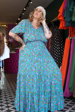 Meet the Dainty Dress in Aqua Bloom, a flowing rayon maxi with an adjustable off-shoulder neckline, elastic waist, tiered skirt and pockets. Handmade in Bali.