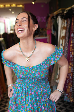 Meet the Mina Maxi Dress in Aqua Moon. A romantic rayon maxi with shirred bodice, off-shoulder ruffles, open tie back, pockets and flowing tiers.