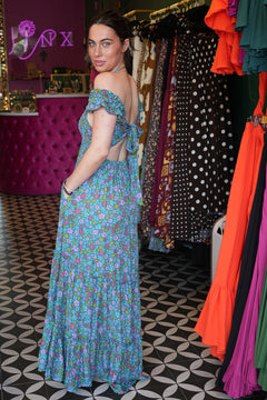 Meet the Mina Maxi Dress in Aqua Moon. A romantic rayon maxi with shirred bodice, off-shoulder ruffles, open tie back, pockets and flowing tiers.