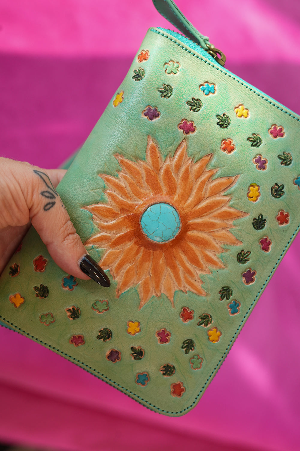 Meet the Mojave Wallet in Desert Mint. A hand tooled leather wallet with sunflower detailing, turquoise accents, card slots, coin compartment and wrist strap.
