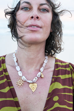 Discover the Sacred Love Necklace in Blush Pearl, featuring irregular freshwater pearls and gold sacred heart, sun and spiral charms by Jinx the Label.