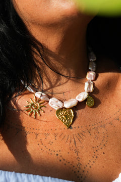 Discover the Sacred Love Necklace in Blush Pearl, featuring irregular freshwater pearls and gold sacred heart, sun and spiral charms by Jinx the Label.
