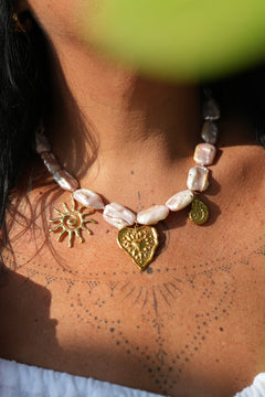 Discover the Sacred Love Necklace in Blush Pearl, featuring irregular freshwater pearls and gold sacred heart, sun and spiral charms by Jinx the Label.