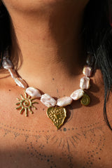 Discover the Sacred Love Necklace in Blush Pearl, featuring irregular freshwater pearls and gold sacred heart, sun and spiral charms by Jinx the Label.