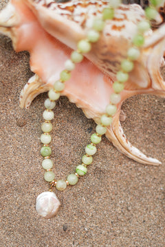 Discover the Sea Garden Necklace in Seafoam, featuring pale green natural stones, gold toned details and an oversized baroque pearl pendant by Jinx the Label.