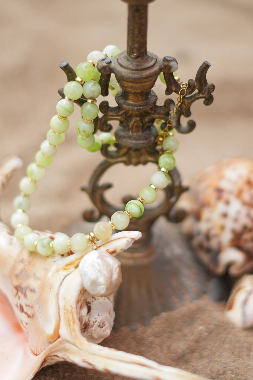 Discover the Sea Garden Necklace in Seafoam, featuring pale green natural stones, gold toned details and an oversized baroque pearl pendant by Jinx the Label.