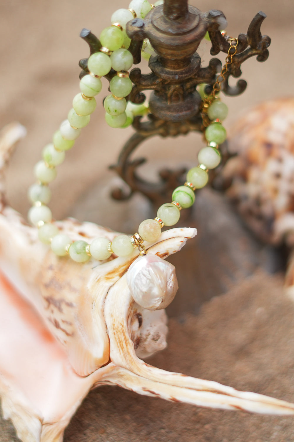 Discover the Sea Garden Necklace in Seafoam, featuring pale green natural stones, gold toned details and an oversized baroque pearl pendant by Jinx the Label.