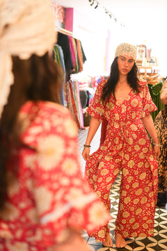 The Sienna Jumpsuit in Wild Daisy Rouge by Jinx the Label, soft rayon with lace sleeves, open back, waist tie and split leg pants for effortless style.