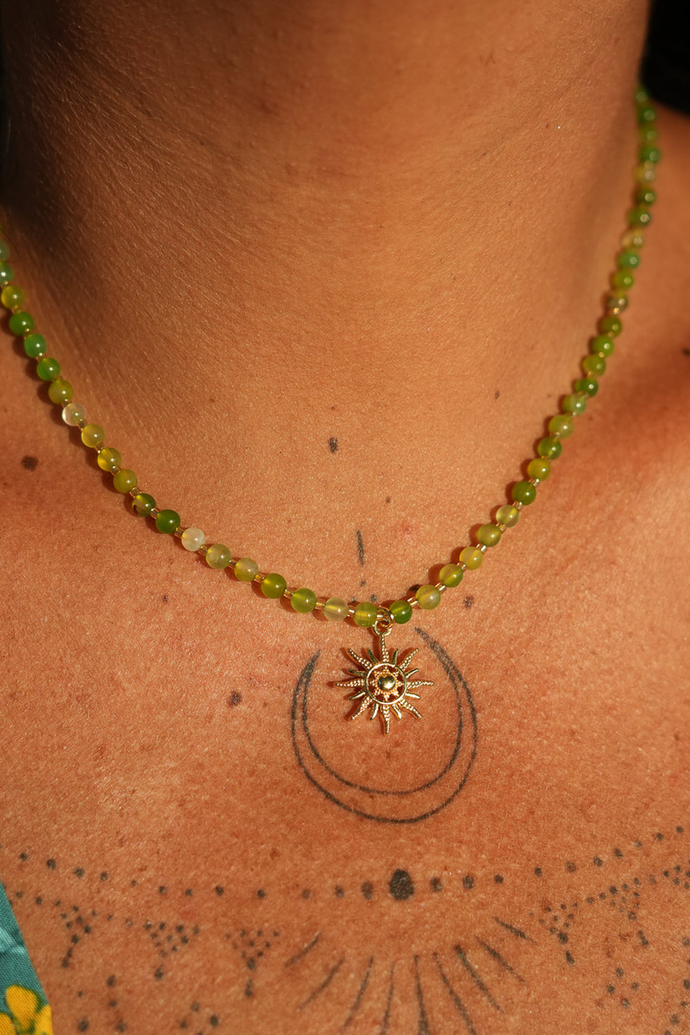 Shop the Solara Sun Necklace in Meadow Green, with natural green stone beads, a radiant gold sun charm and adjustable chain from Jinx the Label.