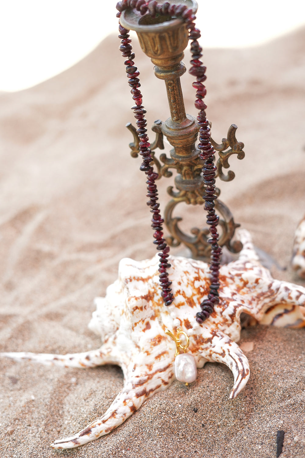 Discover the Wild Heart Necklace in Garnet, featuring deep natural garnet stones, freshwater pearls, a gold toggle and luminous baroque pearl by Jinx the Label.