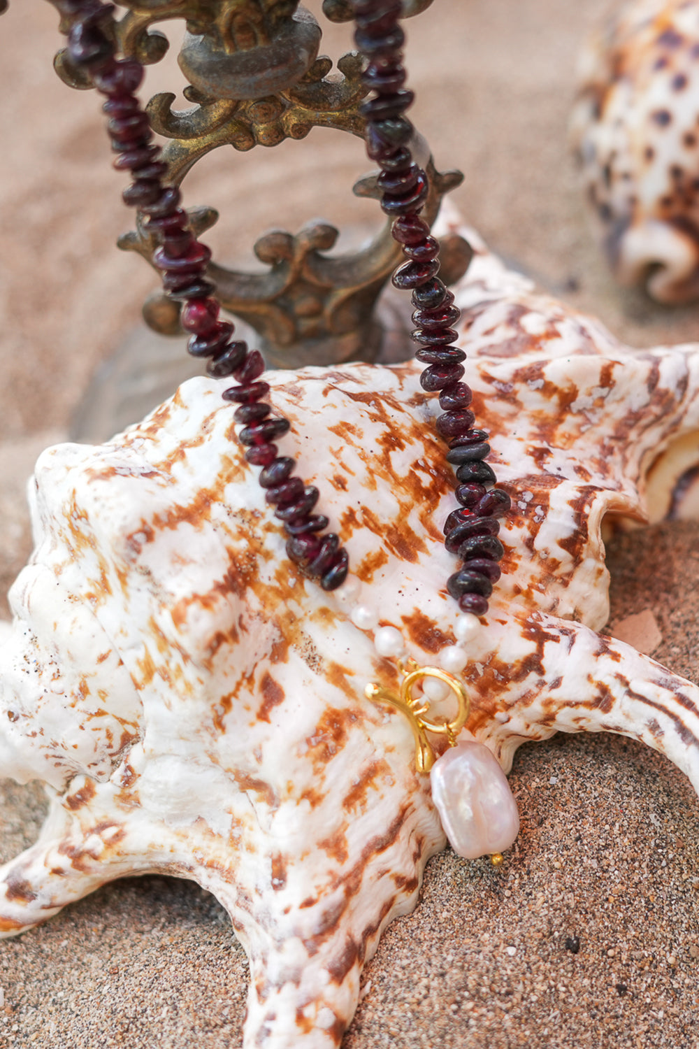 Discover the Wild Heart Necklace in Garnet, featuring deep natural garnet stones, freshwater pearls, a gold toggle and luminous baroque pearl by Jinx the Label.