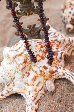 Discover the Wild Heart Necklace in Garnet, featuring deep natural garnet stones, freshwater pearls, a gold toggle and luminous baroque pearl by Jinx the Label.