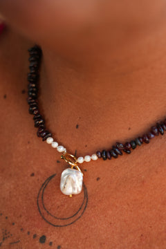 Discover the Wild Heart Necklace in Garnet, featuring deep natural garnet stones, freshwater pearls, a gold toggle and luminous baroque pearl by Jinx the Label.